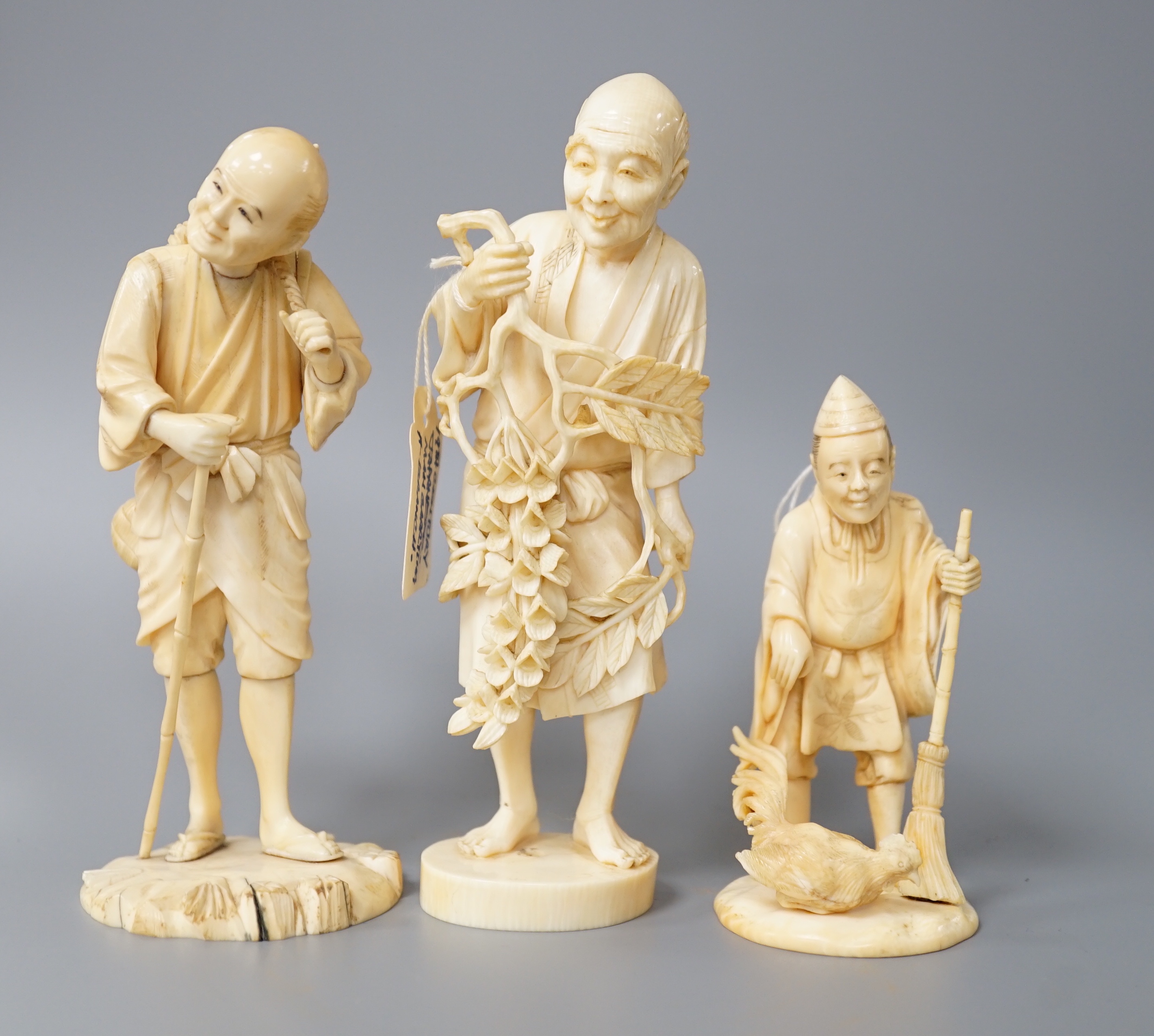 A 19th century Japanese ivory okimono of a gentleman holding a branch, another sectional figure of a gentleman with a walking stick, both signed and another 20th century okimono. Tallest 15.5cm